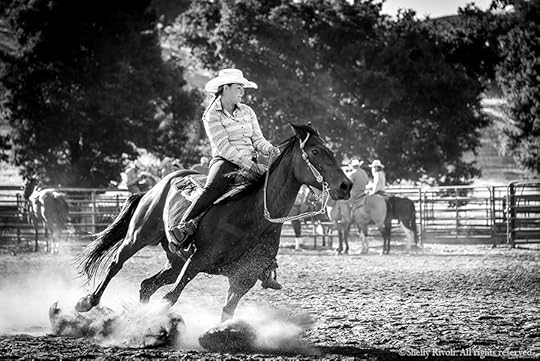 a woman wrangler on horseback digs deep, hooves and dirt flying, in barrel race at rodeo