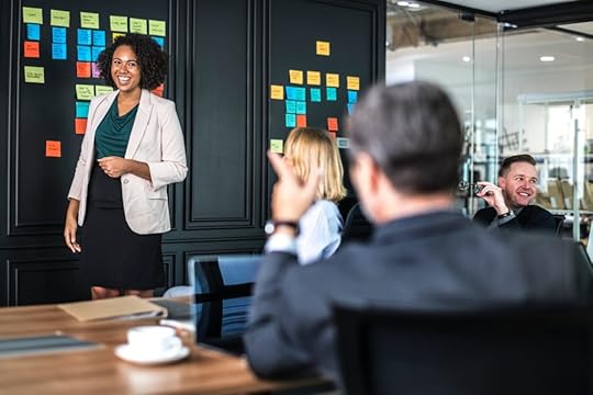 Woman standing in front of group leading conversation at the office.