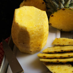 trimmed pineapple on white cutting board inside sheet pan