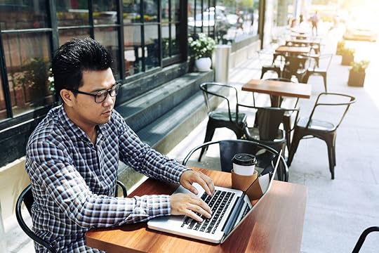 Young Vietnamese businessman working on laptop in outdoor cafe
