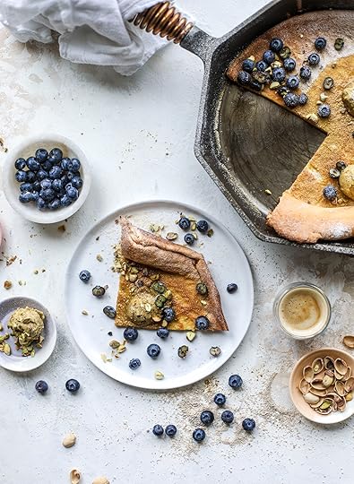 This incredible dutch baby recipe is fluffy and light and perfect for breakfast! It's sprinkled with pistachio sugar and served with pistachio butter and fresh blueberries. It's super easy, simple and always a hit! I howsweeteats.com #dutch #baby #pistachio #blueberry #breakfast