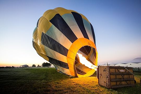 Hot air balloon on its side being lit with fire.