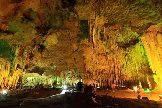 stalagmite and stalactite lit with colored lights in a cave