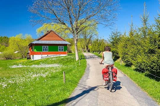 Young woman rides a bike on country road in spring time in the Banica village, Poland