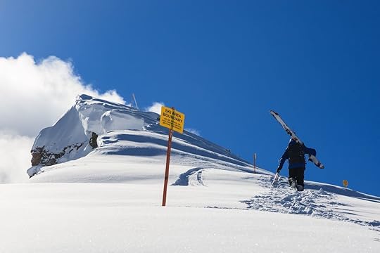 Skier hiking along a cornice in fresh snow