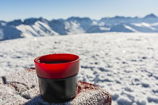 Cup of hot tea on a table with a boundary marker in the winter in the mountains