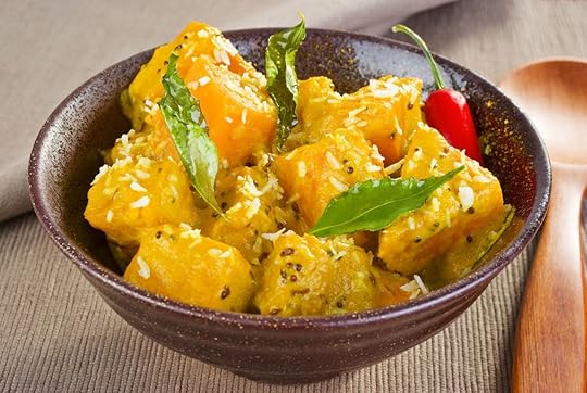 A bowl of chunky curry pumpkin, flavored with coconut, mustard seeds, cumin, chilli and curry leaves