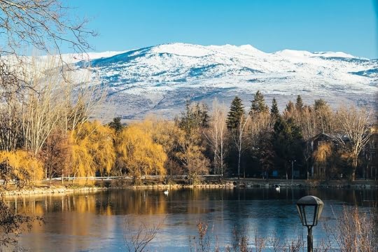 Puigcerda lake in winter with snowy mountain peak and yellow trees reflected