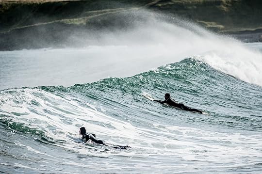 surfers in wetsuits riding waves