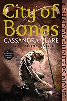 The cover of City Of Bones features a scruffy looking dude knelt before some kind of magic book, with a staff in his hand.