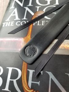 closeup of the bottom of the bookmark; round imprint of a ka'kari