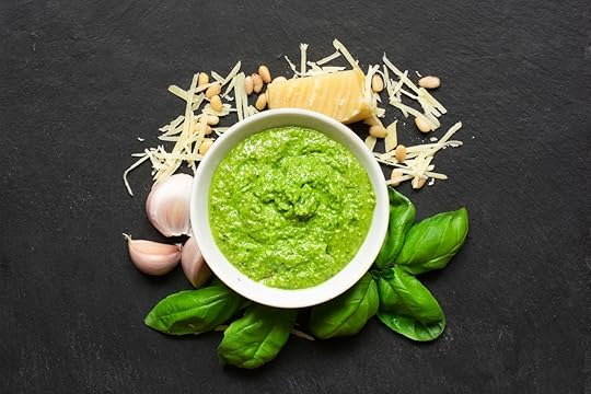 bowl of pesto surrounded by parmesan, pine nuts, garlic, and basil