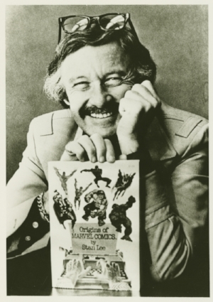 Stan Le e holding Origins of Marvel Comics