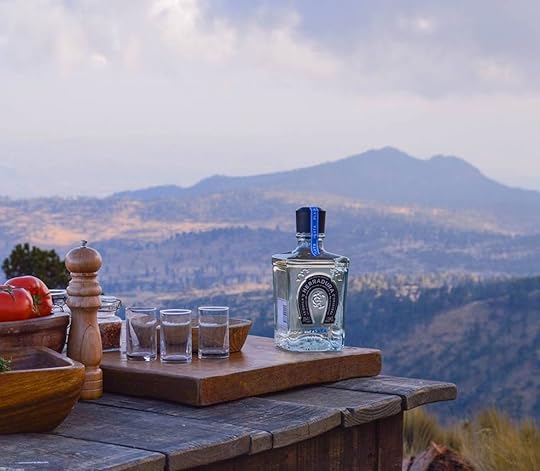Tequila Herradura bottle and glasses in front of a Mexican landscape