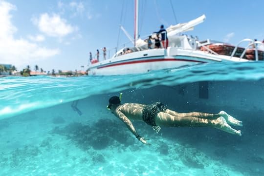 Snorkeler by a boat in the crystal clear water in Aruba