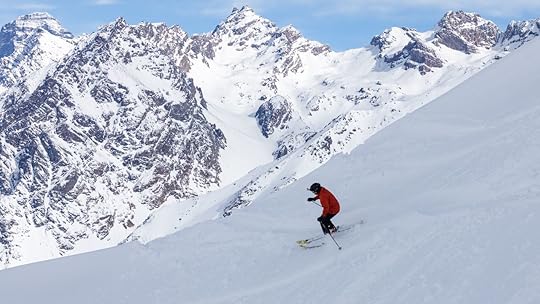 Skier in orange jacket making turns in snow powder
