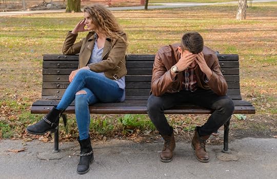 A couple sit on a bench not facing each other, both frustrated.