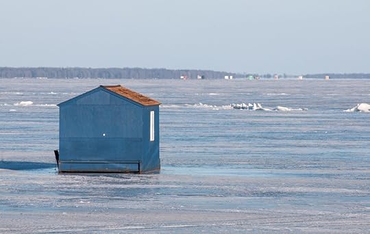 Winter scene and blue ice fishing house on frozen lake
