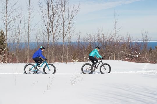couple rides their fat bikes on a trail in the snow