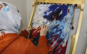 student working on felt project in a loom frame.