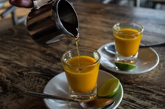 Adding honey to two healthy jamu shots in close-up