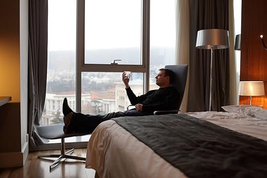 Man in a hotel room with a drink in hand