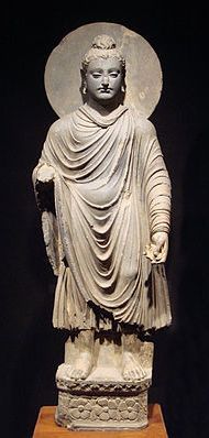 standing Buddha statue with draped garmet and halo