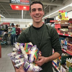 young man in grocery store with bags of marshmallows