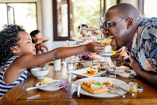 Daughter feeding dad breakfast at hotel restaurant
