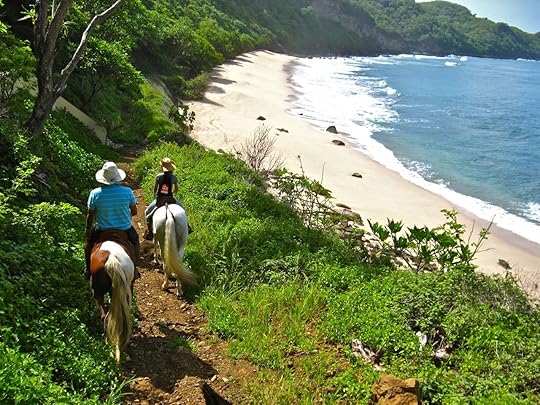 Two people riding horses through the greenery just off a Nicaraguan beach