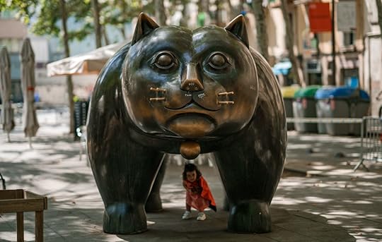 A child plays underneath a bronze cat sculpture in downtown Barcelona