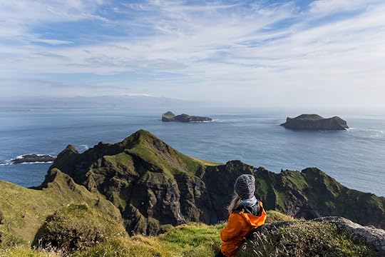 Young female watching the view of ocean on the top of Heimaklettur in Iceland