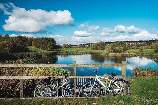 Two bicycles leaning against a fence opposite the picturesque lake in Bathgate, West Lothian, Scotland