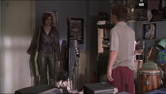Willow is wearing gray leather pants and a purple-ish wrap shirt with frilly sleeves.