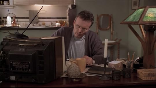 Giles is at his desk, upon which there is now a television in addition to his mystical stuff. He's kind of reading an old book while he's eating and having a big mug of tea. He's wearing two sweaters and neither particularly go with each other or particularly fit well.