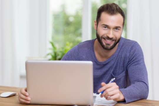 man sitting behind laptop smiling at camera