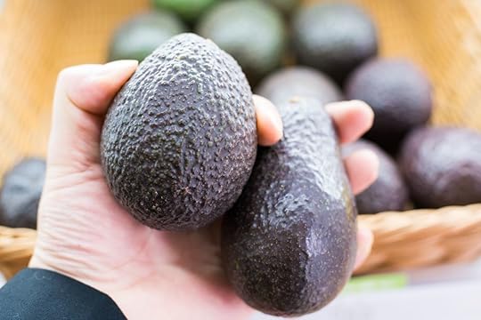 person holding two avocados