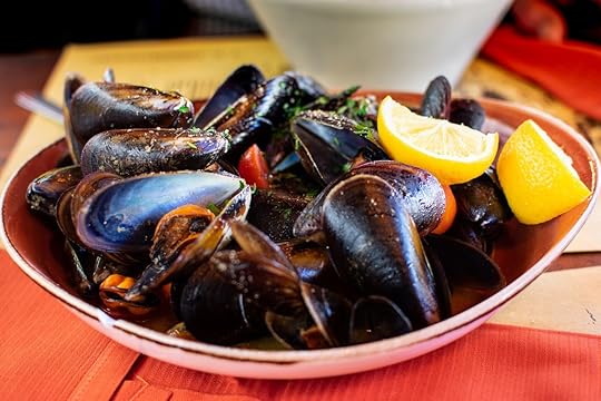 mussels with herbs and lemon, served in a ceramic plate on an orange tablecloth