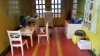 Tiny piglet on chair in dollhouse kitchen with feast on table.