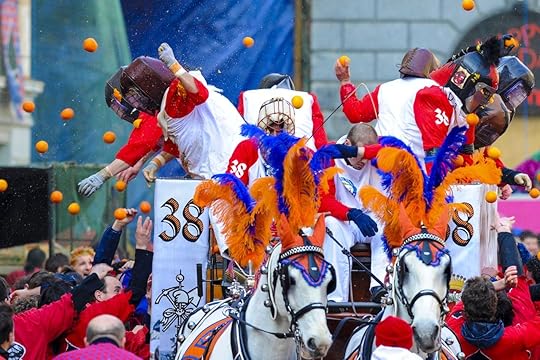 Masked people with traditional helmets throwing oranges during the traditional Carnival Parade of Oranges Battle in Ivrea