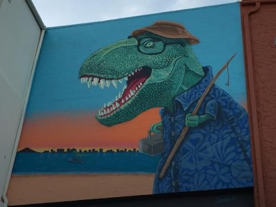 Derek Donnelly's 365 Million Things To Do mural depicts a crusty old T. Rex wearing a fishing cap, glasses, and flowery blue shirt, and carrying a fishing rod and a box of tackle against a Florida sunset. On the body of water behind him, you can just barely make out a raptor on a jet-ski. 