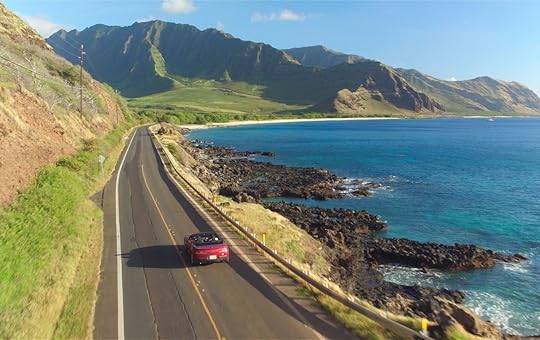 Red convertible car driving along the picturesque coastal road