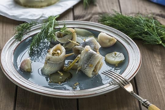 Plate of pickled fish rolls with pickles and dill on the side