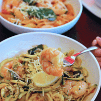 shrimp on fork over bowl of zoodles