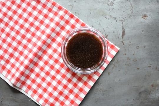 A jar of dumpling dipping sauce sitting on a red and white checked cloth.
