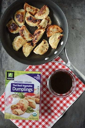 Cooked dumplings in the pan, along with dipping sauce and a package of Nasoya dumplings.