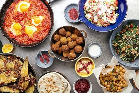 Overhead image of traditional jewish and middle eastern food: falafel, fattoush, tabouli, shakshuka, balila, hummus, roasted eggplants and spicy beetroot dip