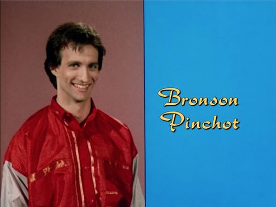 Bronson Pinchot, still in that '80s windbreaker, on a vertically split screen with his name in that same hideous yellow font but on a field of intense blue that clashes with every other color on screen.