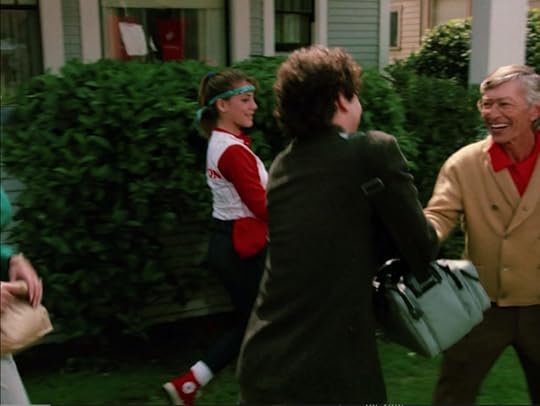 Larry crosses in front of a teen girl in a ponytail and sweatband, wearing a baseball uniform, red Chuck Taylors, and a red baseball cap tucked in her waistband. Larry shakes hands enthusiastically with an old Asian man in a brown cardigan.