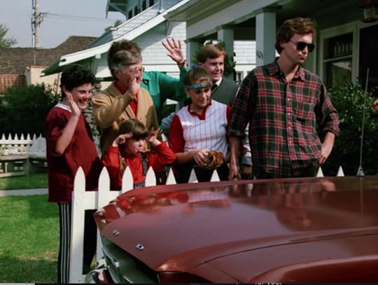 Larry's family stands beside the car waving him off. There's a boy in a red shirt and track pants, a little girl in a jumper and red shirt, the other characters already mentioned, and a dude with kind of a shaggy mullet-type hairdo and a red plaid shirt. He's wearing sunglasses and leaning back on the fence, as opposed to standing behind it with the rest of the family.